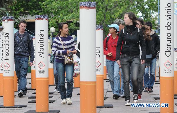 People walk past a giant cigarette installation placed at the Fabiani Plaza, in Montevideo, Uruguay, on Nov. 17, 2010. 