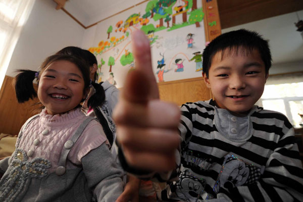 Zhang Weishi (R), 9, and Liu Chongyun (L), 8, play in the living room of the Children's Village in Tianjin on Nov 20, 2010. 