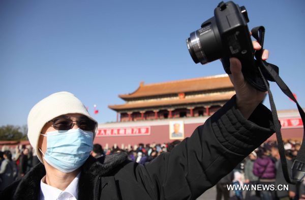 A man takes photos for himself on the Tian'anmen Square in a clear windy day in Beijing, capital of China, Nov. 21, 2010. Beijing confronted a cold wave on Sunday with temperature predicted to drop to minus three degrees celsius at night. (Xinhua/Chen Xiaogen) (cxy) 