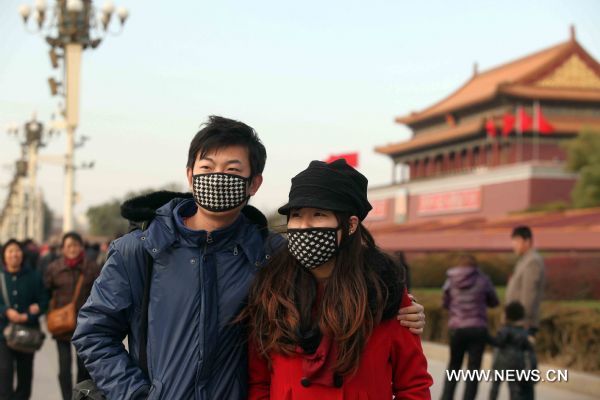 Tourists pose for a photo on the Tian'anmen Square in a clear windy day in Beijing, capital of China, Nov. 21, 2010. 
