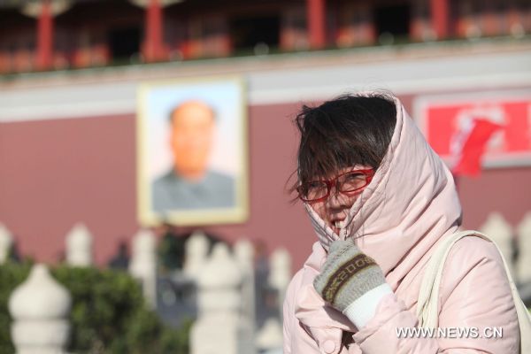 A woman tries to warm herself on the Tian'anmen Square in a clear windy day in Beijing, capital of China, Nov. 21, 2010.
