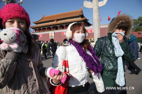 Tourists with face masks walk on the Tian'anmen Square in a clear windy day in Beijing, capital of China, Nov. 21, 2010. 