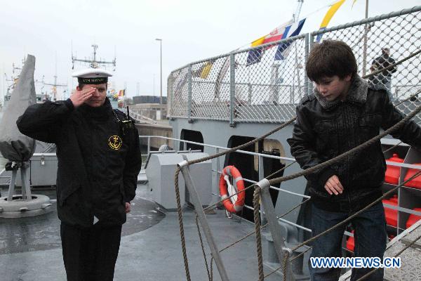 A sailor salutes as a boy visits on the Norwegian mine countermeasures vessel called 'Penzance' at the navy base in Zeebrugge, Belgium, Nov. 21, 2010. 