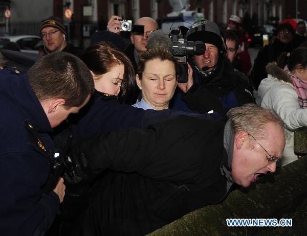 A protester is arrested after trying to stop the car carrying Irish Tourism, Culture and Sport Minister Mary Hanafin as she arrives for a cabinet meeting at the Government Buildings, in Dublin, Ireland, Nov. 21, 2010. 