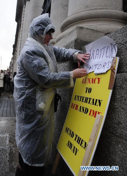 A protester writes &apos;Traitors&apos; on a placard to protest against the talks between the government and the IMF and the ECB in front of the Government Buildings, in Dublin, Ireland, Nov. 21, 2010. 