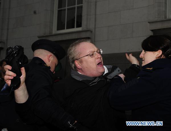 A protester is arrested after trying to stop the car carrying Irish Tourism, Culture and Sport Minister Mary Hanafin as she arrives for a cabinet meeting at the Government Buildings, in Dublin, Ireland, Nov. 21, 2010.