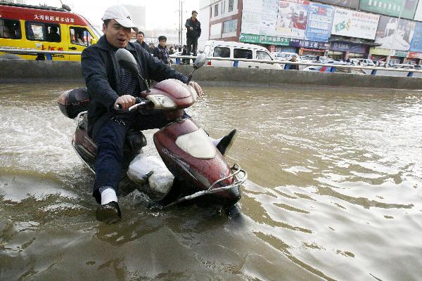 A citizen rides through a waterlogged road in Zhengzhou, capital of central China's Henan Province, Nov. 22, 2010. 