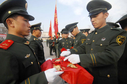 Soon-to-be-retired soldiers (R) detach their epaulets and buttonhole pins at a farewell ceremony held at Ningxia Paramilitary Police Corps in Yinchuan, Ningxia Hui autonomous region, Nov 23, 2010. [Xinhua] 