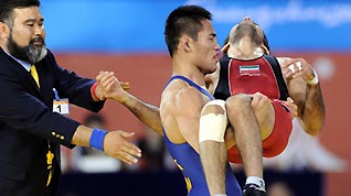 Gao Feng of China carries Iran's injured wrestler S. Ahmadi as they leave the court after their bronze medal match in the men's 60kg freestyle wrestling at the 16th Asian Games in Guangzhou, Nov 23, 2010.