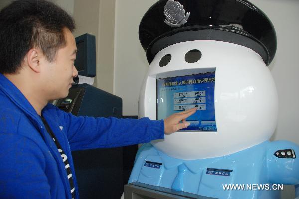 A citizen uses the exit and entry service robot named 'A Pang' in Quanzhou City's exit and entry administration, southeast China's Fujian Province, Nov. 24, 2010.