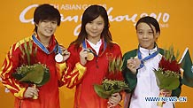 China's He Zi (C), Shi Tingmao (L) and Choi Sut Ian of Macao of China pose on the podium of the women's 3m springboard final of Diving event at the 16th Asian Games in Guangzhou, south China's Guangdong Province, Nov. 26, 2010.