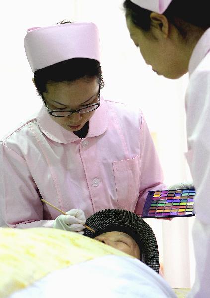 Embalmer Chen Yu (L) applies makeup for a deceased in Shanghai, east China, on Nov. 28, 2010. 