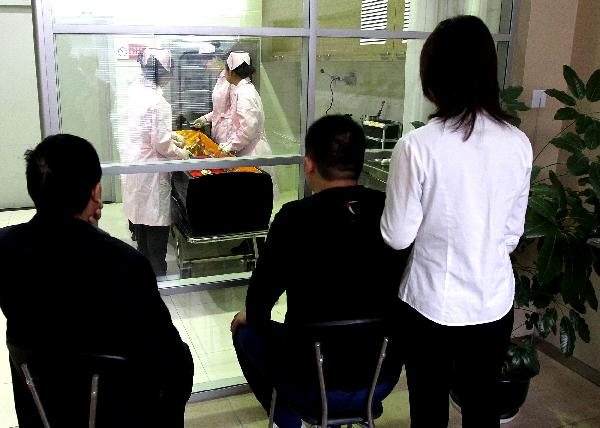 Family members of a deceased watches embalmers working in Shanghai, east China, on Nov. 27, 2010. 