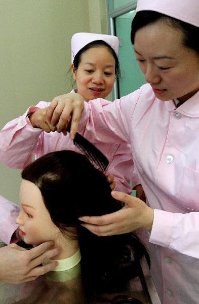 Zong Rui (R), an experienced embalmer, teaches a new colleague how to comb for the deceased in Shanghai, east China, on Nov. 26, 2010. 