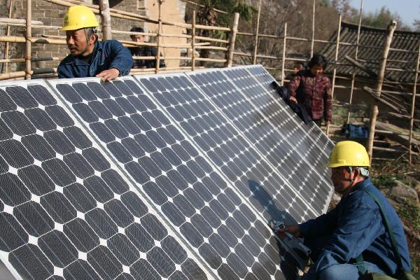 State Grid staffs work with photovotaic battery panels in Neixiang County, central China's Henan Province, Nov 29, 2010.