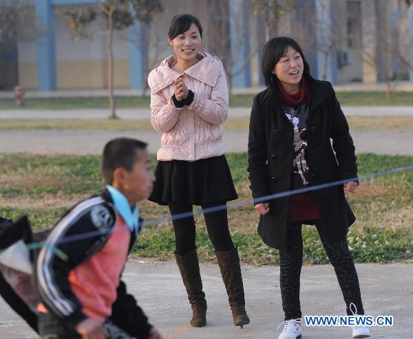 Orphans, whose parents died of AIDS, play a game with their teachers at the Zhonghua Red Ribbon Home, an orphanage in Shangcai County, central China's Henan Province, Nov. 30, 2010. 