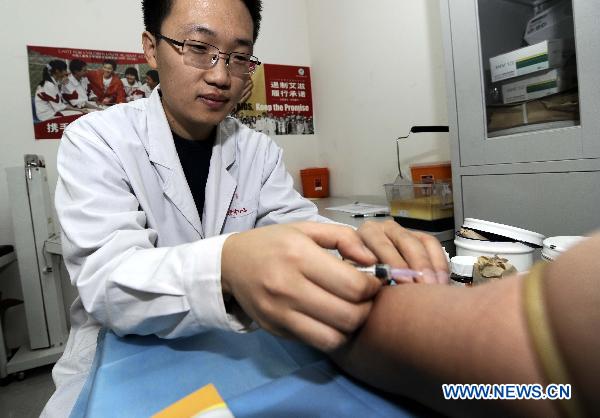 Liu Zhongquan, a staff member of the AIDS/STD station of the Tianjin centers for Disease Control and Prevention, draws blood for a client in Tianjin, north China, Nov. 30, 2010. 