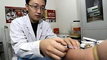 Liu Zhongquan, a staff member of the AIDS/STD station of the Tianjin centers for Disease Control and Prevention, draws blood for a client in Tianjin, north China, Nov. 30, 2010.
