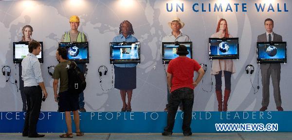 People look at UN climate wall in the climate village during the United Nations Framework Convention on Climate Change (COP-16), in the Mexican seaside resort of Cancun, on Nov. 30, 2010. 