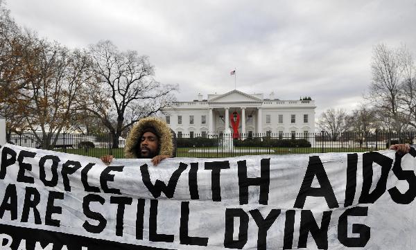 An activist holds a banner during a mock funeral for people who died of the HIV/AIDS in the past year, marking the World AIDS Day and calling for US President Barack Obama to fulfill his promise to fund global AIDS, in front of the White House in Washington D.C., capital of the United States, Dec. 1, 2010.