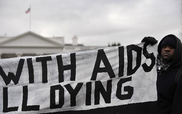 An activist holds a banner during a mock funeral for people who died of the HIV/AIDS in the past year, marking the World AIDS Day and calling for US President Barack Obama to fulfill his promise to fund global AIDS, in front of the White House in Washington D.C., capital of the United States, Dec. 1, 2010. 