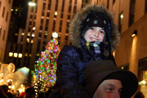 A man and his child pose in front of the Christmas tree at the Rockefeller Center in New York Dec. 4, 2010. The whole city is in the festive mood as Christmas Day draws near. 