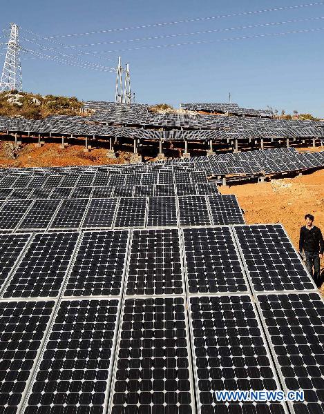 File photo taken on Jan. 5, 2010 shows a man walking next to solar panels in a solar power plant in Shilin Yi Autonomous Prefecture, southwest China&apos;s Yunnan Province. 