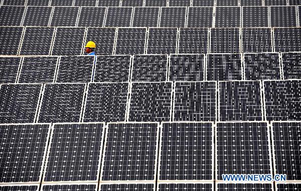 File photo taken on May 24, 2010 shows a man walking among solar panels in a solar power plant in Shilin Yi Autonomous Prefecture, southwest China&apos;s Yunnan Province.