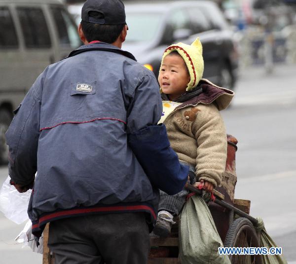 A sweet potato vender puts his child near his stove to keep warm on the street in Nantong City, China's Jiangsu Province, Dec. 6, 2010.