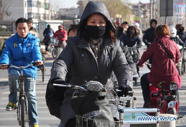 People are seen in thick clothes on the street in Cangzhou, north China's Heibei Province, Dec. 6, 2010. 