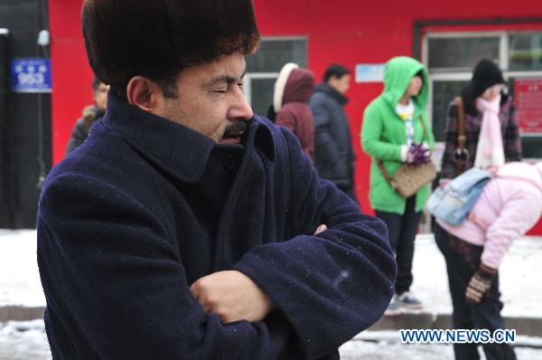 A man in thick clothes waits at a bus stop on the street in Urumqi, capital of northwest China's Xinjiang Uygur Autonomous Region, Dec. 3, 2010. 