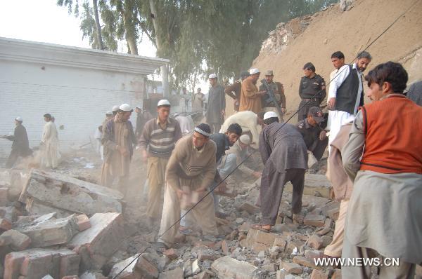 People clear the rubble at the site of a suicide bombing in northwest Pakistan&apos;s Mohmand region on December 6, 2010. Two suicide bombers Monday targeted a meeting of pro-government tribal elders in a Pakistani tribal region, killing at least 50 people with 120 others injured. 