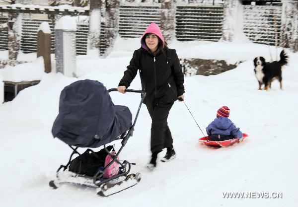A woman walks on a snowy street with her child in Helsinki, Finland, Dec. 7, 2010. 