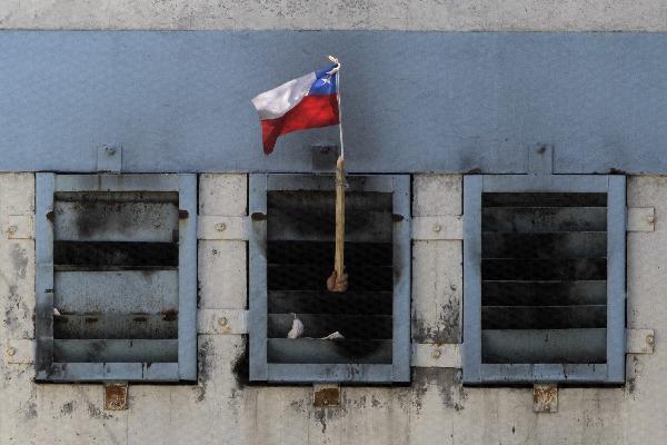 An inmate waves a Chilean flag from inside San Miguel public prison, after a fire broke out in the building, killing 81 inmates, in Santiago December 8, 2010.
