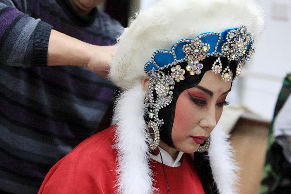 Xing Meizhu from Heilongjiang Peking Opera Troupe has makeup applied backstage prior to performing 'Lu Gou Xiao Yue' (the moon at dawn in Lu Gou) in Beijing, capital of China, Dec. 8, 2010. 
