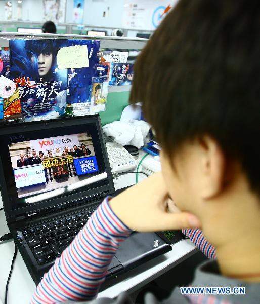 A staff member of Youku.com, China's largest online video company, watches a video on Youku's debut in the New York Stock Exchange, at Youku's office in Beijing, capital of China, Dec. 9, 2010. 