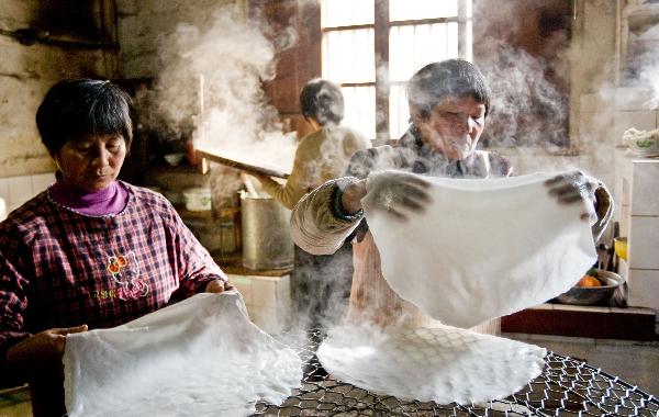 Villagers make Tenggeng, a traditional snack made of rice, in the Sizhai Village of Zhuji City, east China's Zhejiang Province, Dec. 8, 2010. 