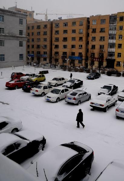 People walk in a snow-coverd residential community in Ulan Hot, north China's Inner Mongolia Autonomous Region, Dec. 10, 2010.