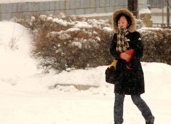 A woman walks on the snow-covered street in Ulan Hot, north China's Inner Mongolia Autonomous Region, Dec. 10, 2010.