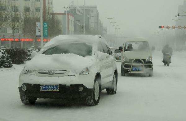 Vehicles run on the snow-covered street in Ulan Hot, north China's Inner Mongolia Autonomous Region, Dec. 10, 2010.