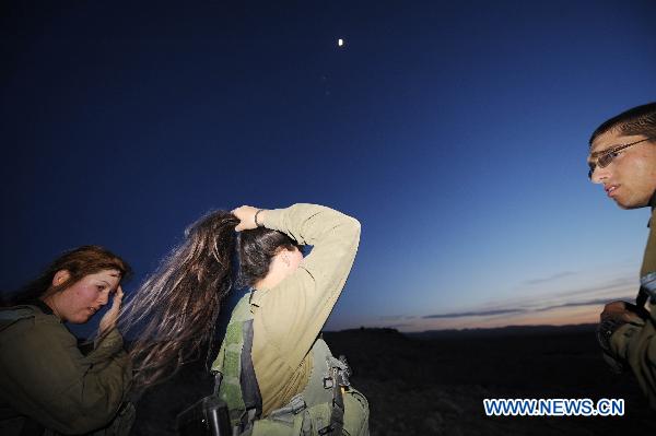 A female Israeli Defense Force (IDF) soldier comb her hair after a drill in desert near Israel-Egypt border and Israeli Southern City of Sede Boker, on Dec.13, 2010. 