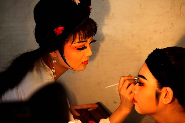 Actors put on face-painting before staging a repertoire of Shaoxing Opera in Tongpu Village of Rui'an City, east China's Zhejiang Province, Dec. 13, 2010. 