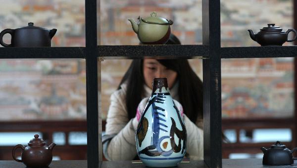 A student takes photos of artworks displayed at a folk art show held in Nantong Textile Vocational College in Nantong, east China's Jiangsu Province, Dec. 14, 2010. 