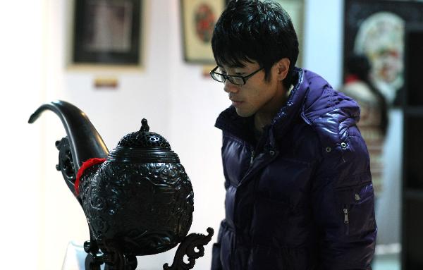 A student looks at a huge smoking pipe at a folk art show held in Nantong Textile Vocational College in Nantong, east China's Jiangsu Province, Dec. 14, 2010. 