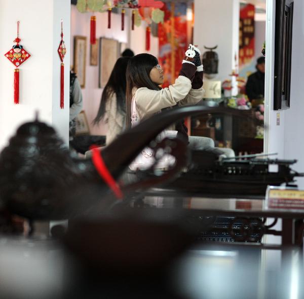 A student takes photos at a folk art show held in Nantong Textile Vocational College in Nantong, east China's Jiangsu Province, Dec. 14, 2010.