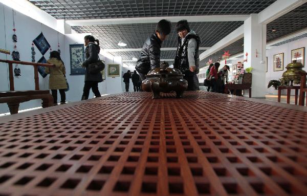 Visitors admire artworks displayed at a folk art show held in Nantong Textile Vocational College in Nantong, east China's Jiangsu Province, Dec. 14, 2010.