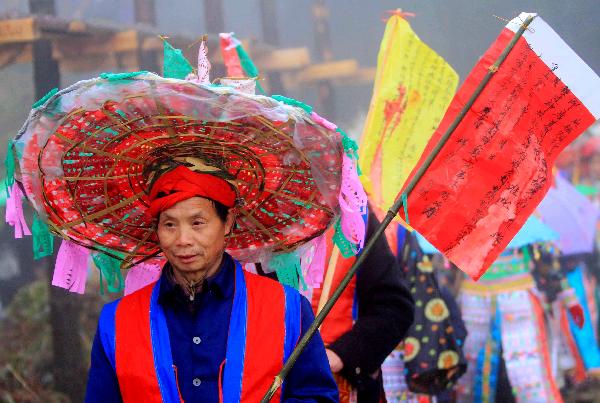 A teacher leads young men and their families to parade during the debutant for young men of Yao ethnic group in Gaodian Village of Rongshui Miao Autonomous County, south China's Guangxi Zhuang Autonomous Region, Dec. 12, 2010. 