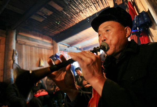 A teacher plays horn at the debutant for young men of Yao ethnic group in Gaodian Village of Rongshui Miao Autonomous County, south China's Guangxi Zhuang Autonomous Region, Dec. 12, 2010. 