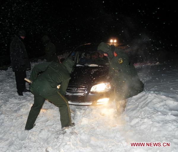 Rescuers clean the snow for a stranded car at a national highway linking Jarud Qi and Holin Gol within north China's Inner Mongolia Autonomous Region, early on Dec. 15, 2010. 