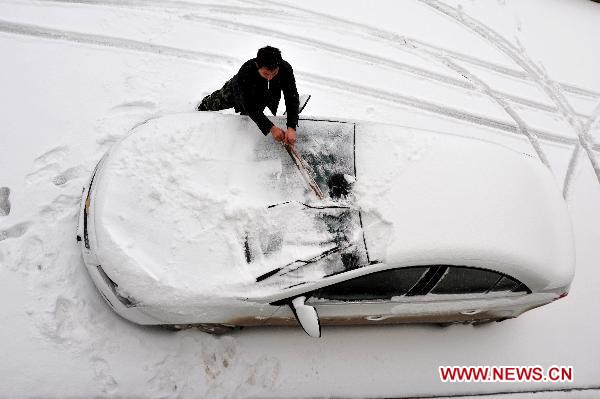 A man clears snow covering his car in Huaping Township of Enshi, central China's Hubei Province, Dec. 15, 2010. 